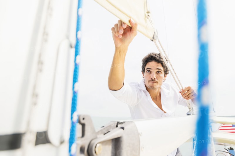Hispanic man adjusting rigging on sailboat