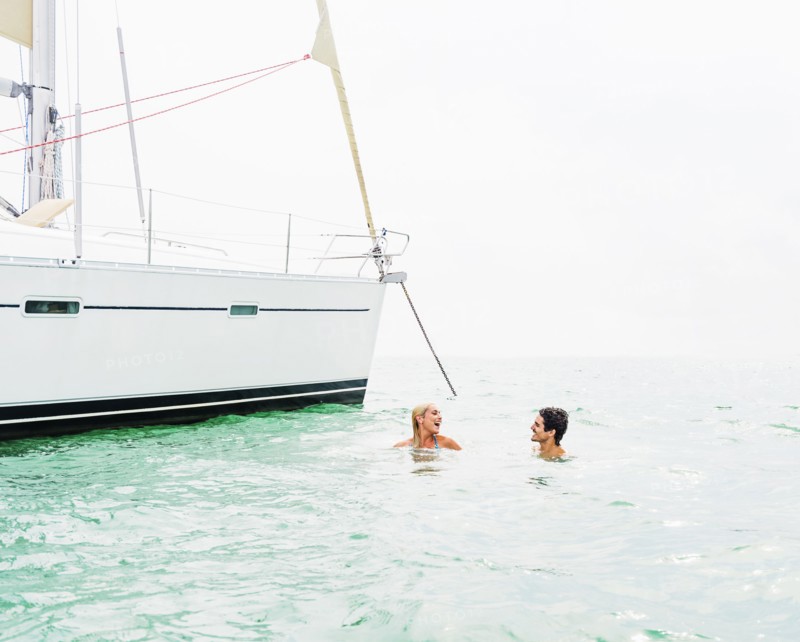 Couple swimming near sailboat
