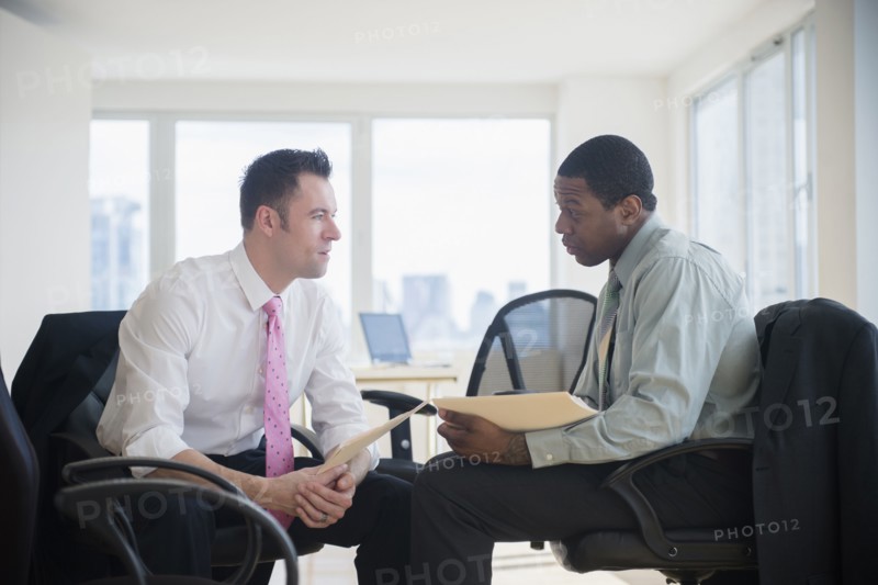 Businessmen holding folders in office
