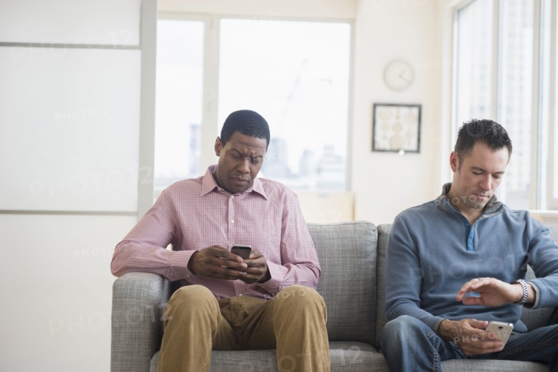 Men with cell phones waiting on sofa
