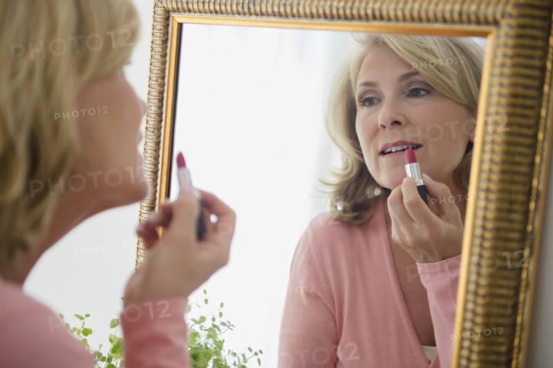 Caucasian woman applying lipstick in mirror