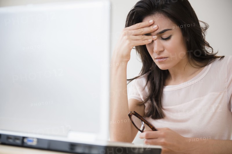 Stressed woman rubbing her forehead at laptop