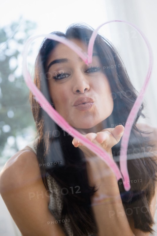Close up of woman blowing a kiss through heart