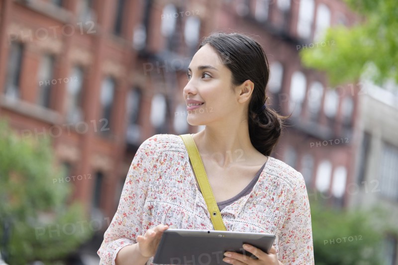 Hispanic woman using digital tablet in city