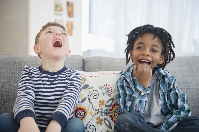 Boys laughing on living room sofa