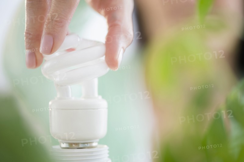 Mixed race woman holding fluorescent light bulb