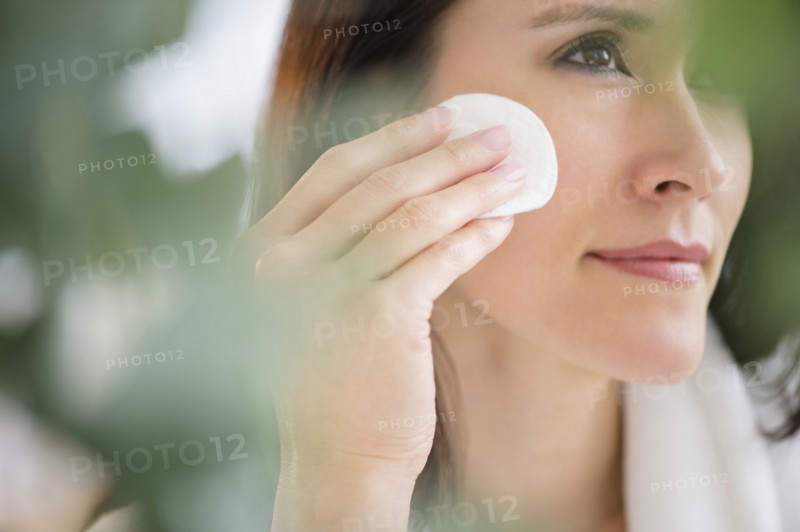 Mixed race woman patting makeup on face