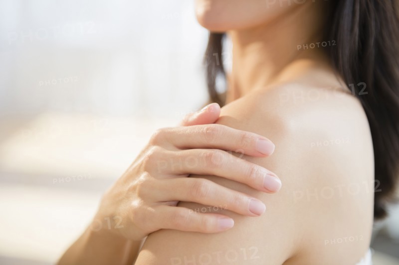Mixed race woman rubbing lotion into skin