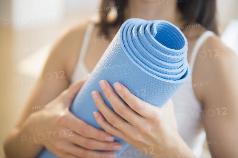Mixed race woman holding exercise mat