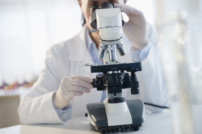 Mixed race scientist using microscope in laboratory