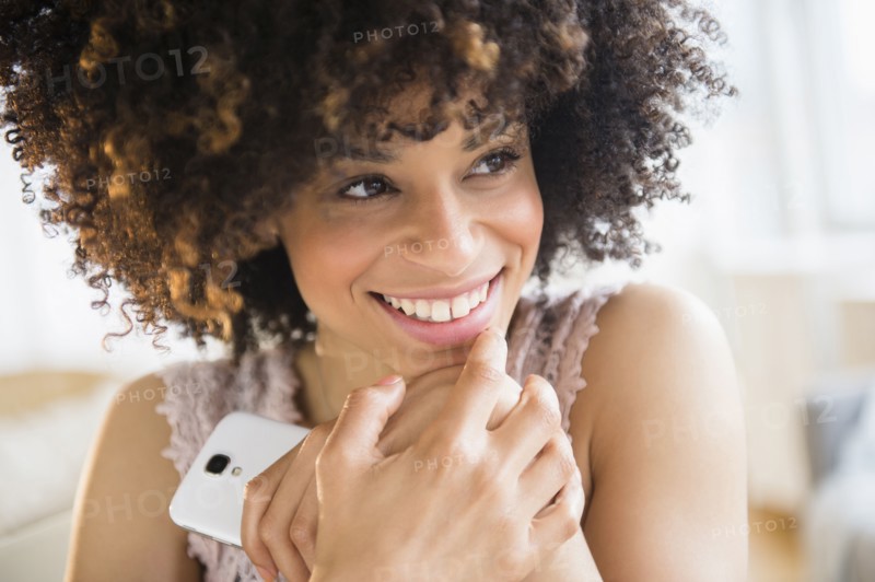 Smiling mixed race woman holding cell phone