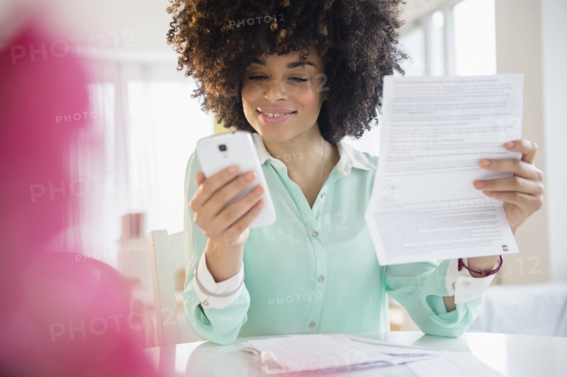 Mixed race woman paying bill with cell phone