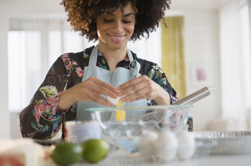 Mixed race woman cracking egg