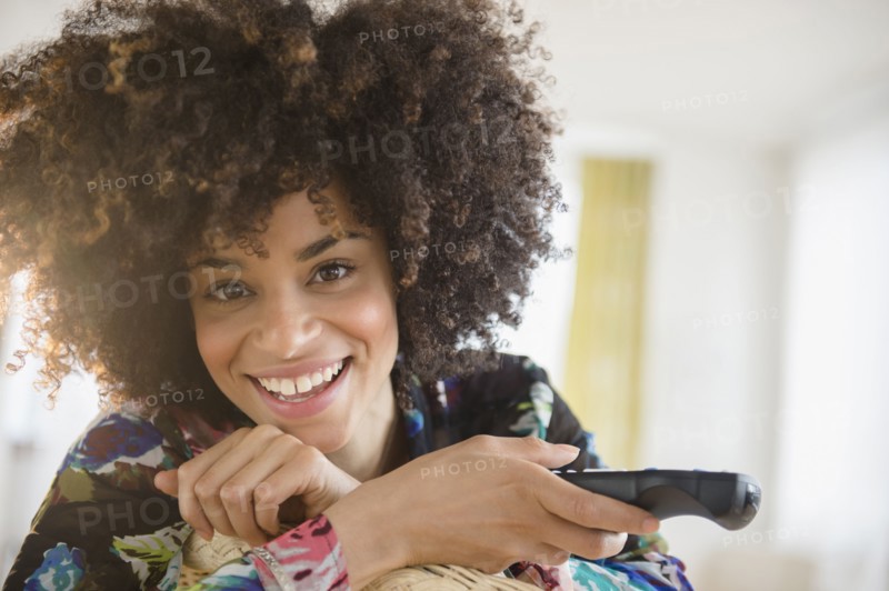 Mixed race woman holding television remote control