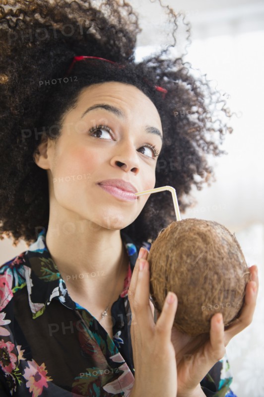 Mixed race woman drinking coconut water with straw