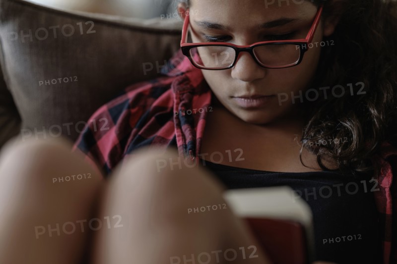 Mixed race girl reading on sofa