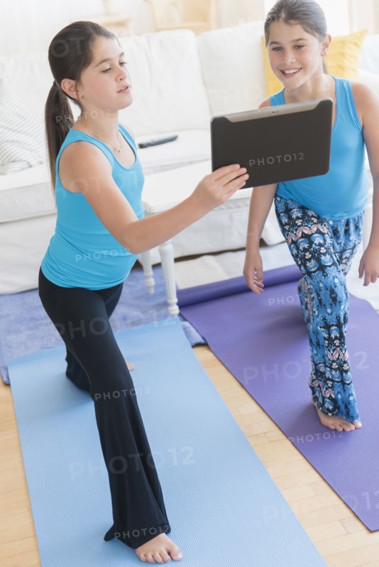 Caucasian twin sisters learning yoga with digital tablet