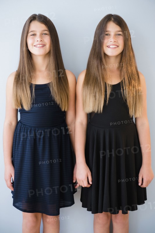 Caucasian twin sisters wearing dresses