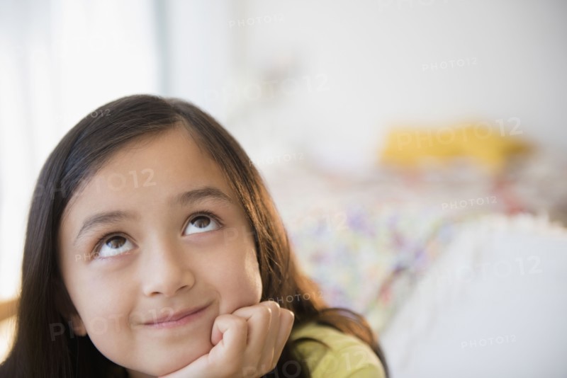 Smiling girl daydreaming with hand on chin