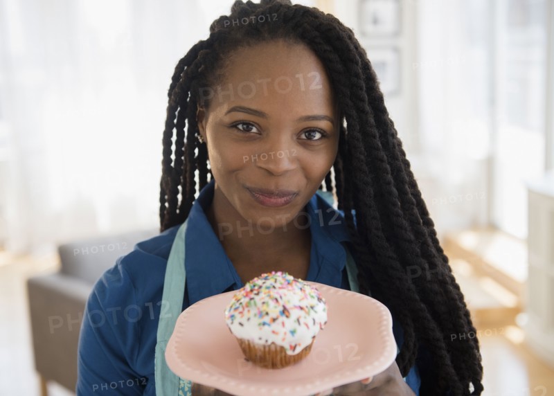 Black woman holding cupcake on plate