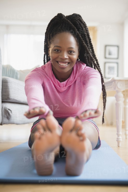 Black woman practicing yoga in living room