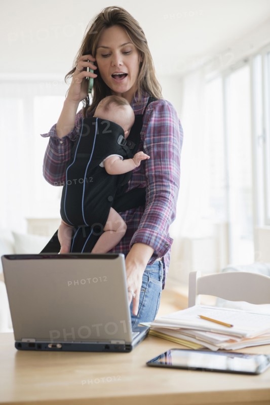 Mother working at home with new baby daughter