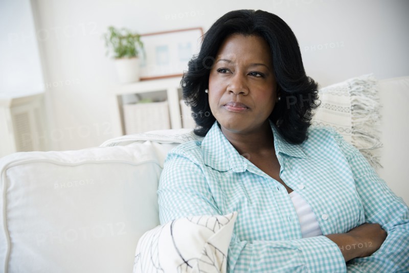 Unhappy Black woman sitting on sofa
