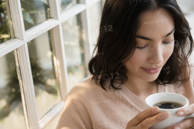 Hispanic woman drinking cup of coffee