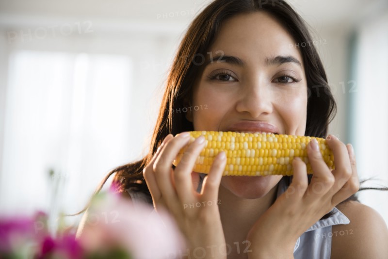 Hispanic woman eating corn on the cob