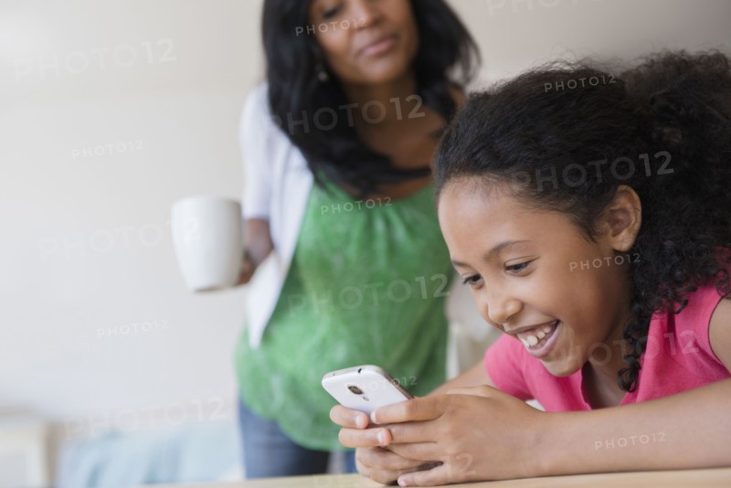 Mother watching daughter use cell phone