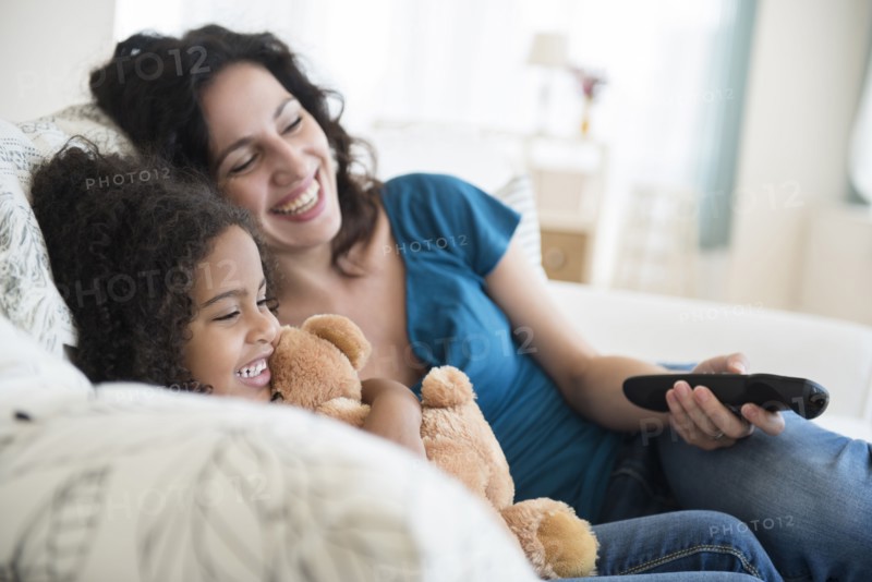 Mother and daughter watching television on sofa