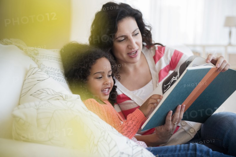 Mother and daughter reading on sofa