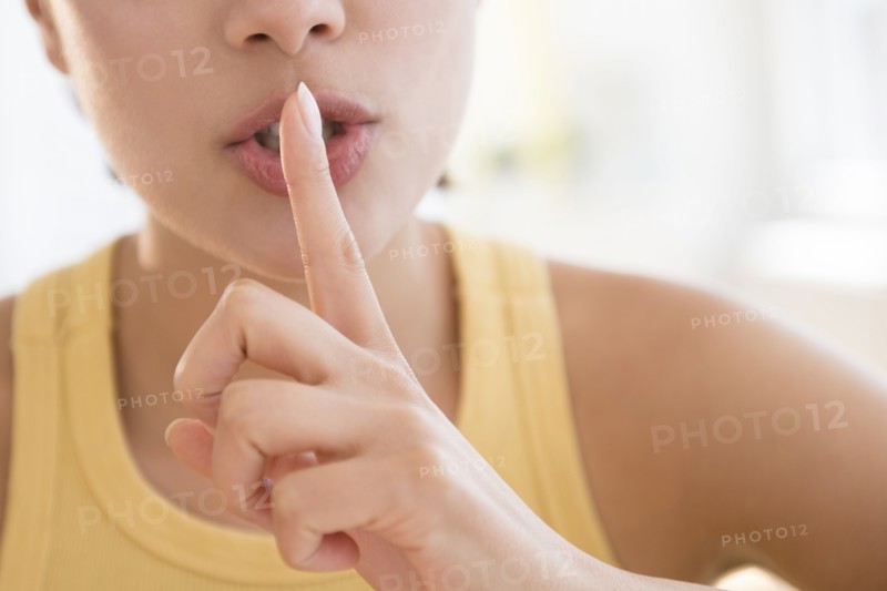 Close up of Hispanic woman shushing