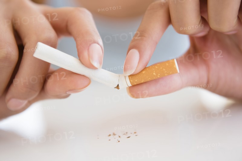 Close up of Hispanic woman breaking cigarette