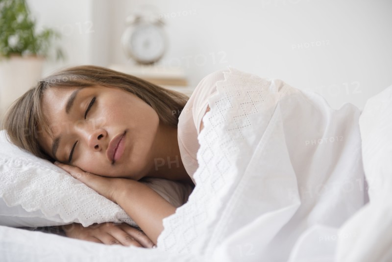Mixed race woman sleeping in bed