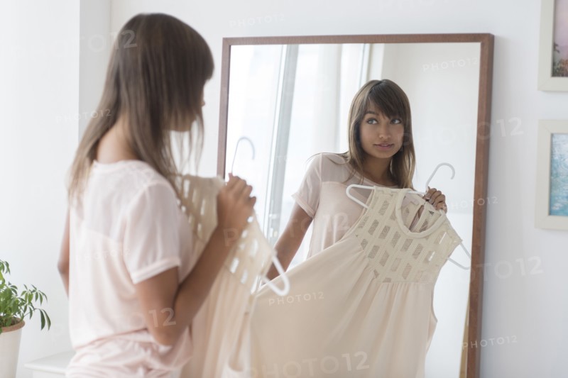 Mixed race woman examining dress in mirror