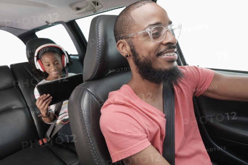 Black father and daughter driving in car