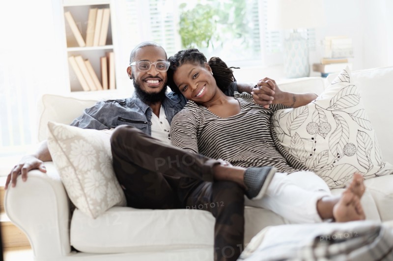 Black couple smiling on sofa