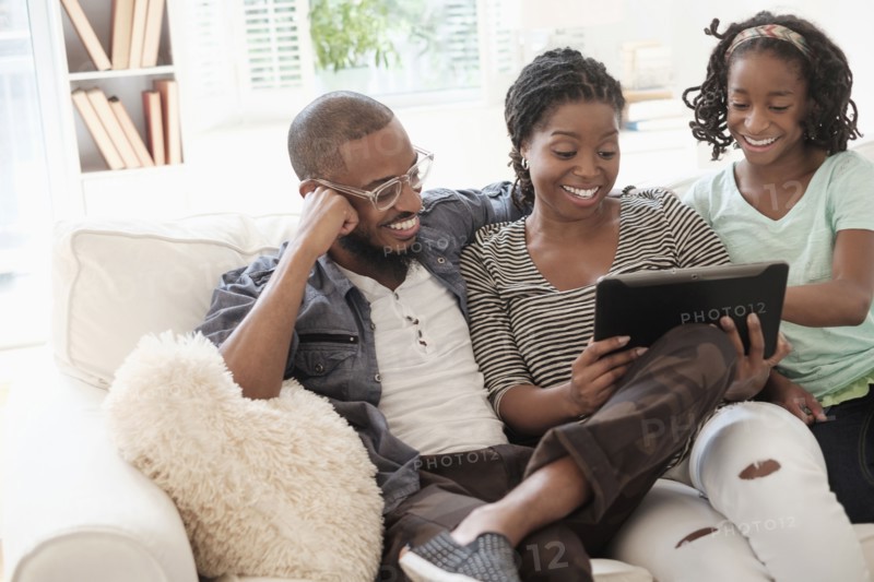 Black family using digital tablet on sofa