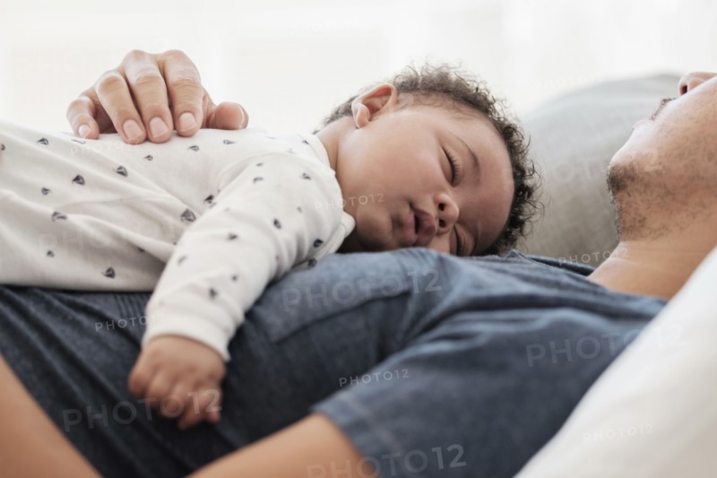 Father and baby son sleeping on bed
