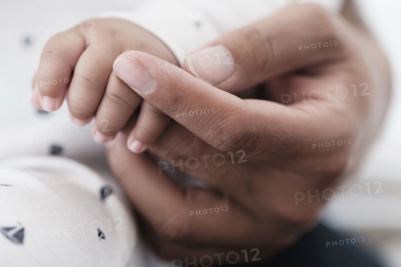 Close up of father holding hand of baby son