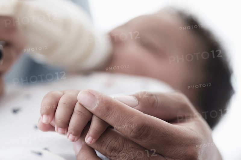 Close up of father holding hand of baby son
