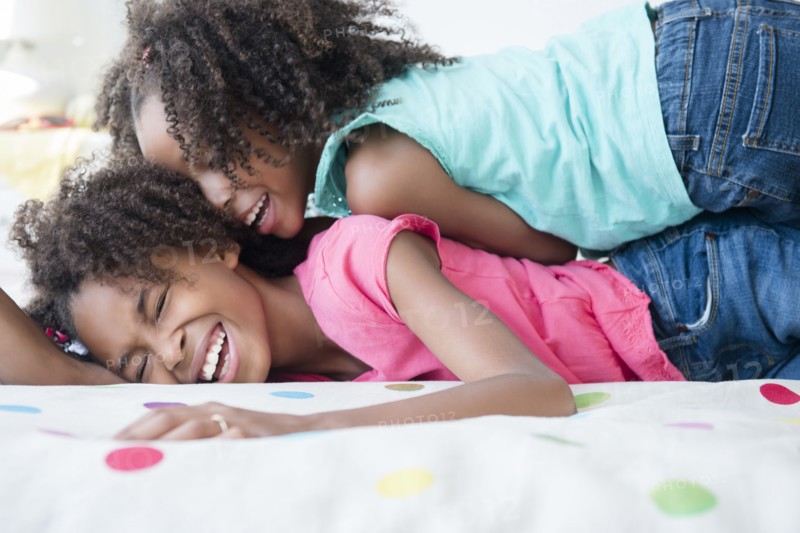 Mixed race sisters playing on bed
