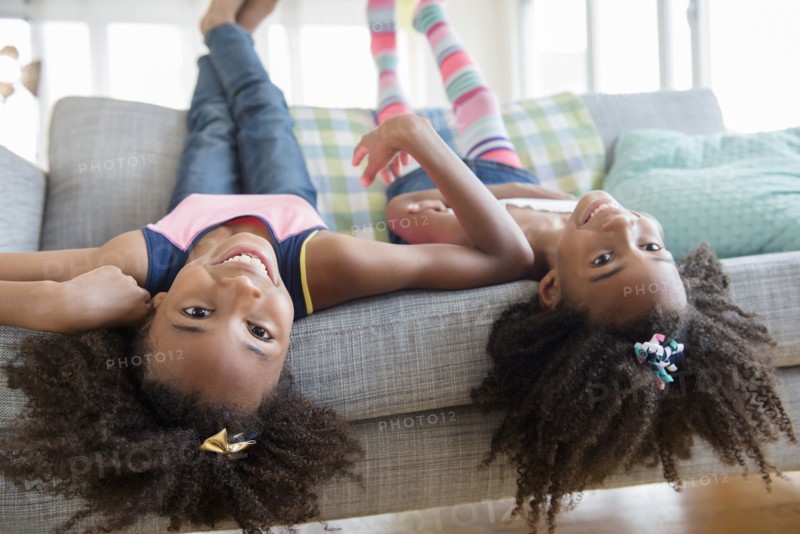 Mixed race sisters laying on sofa