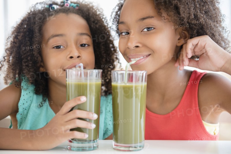 Mixed race sisters drinking healthy juice