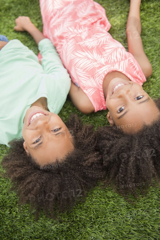 Mixed race sisters laying in grass