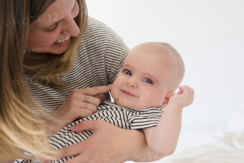 Caucasian mother holding baby daughter on bed