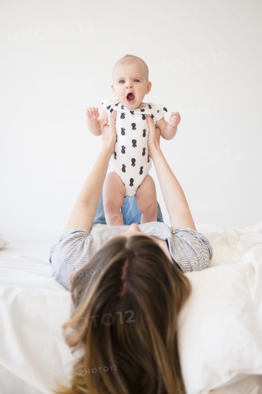 Caucasian mother holding baby daughter on bed