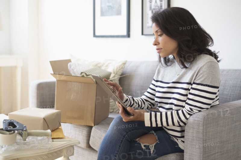 Mixed race business owner using digital tablet on sofa