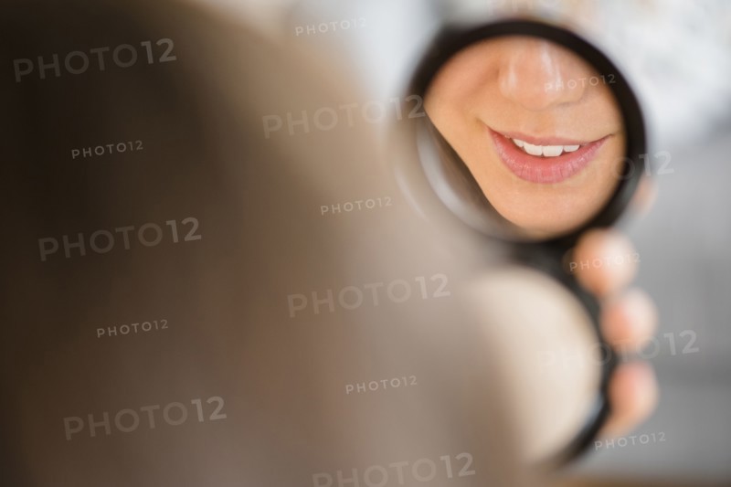 Mixed race woman admiring herself in compact mirror